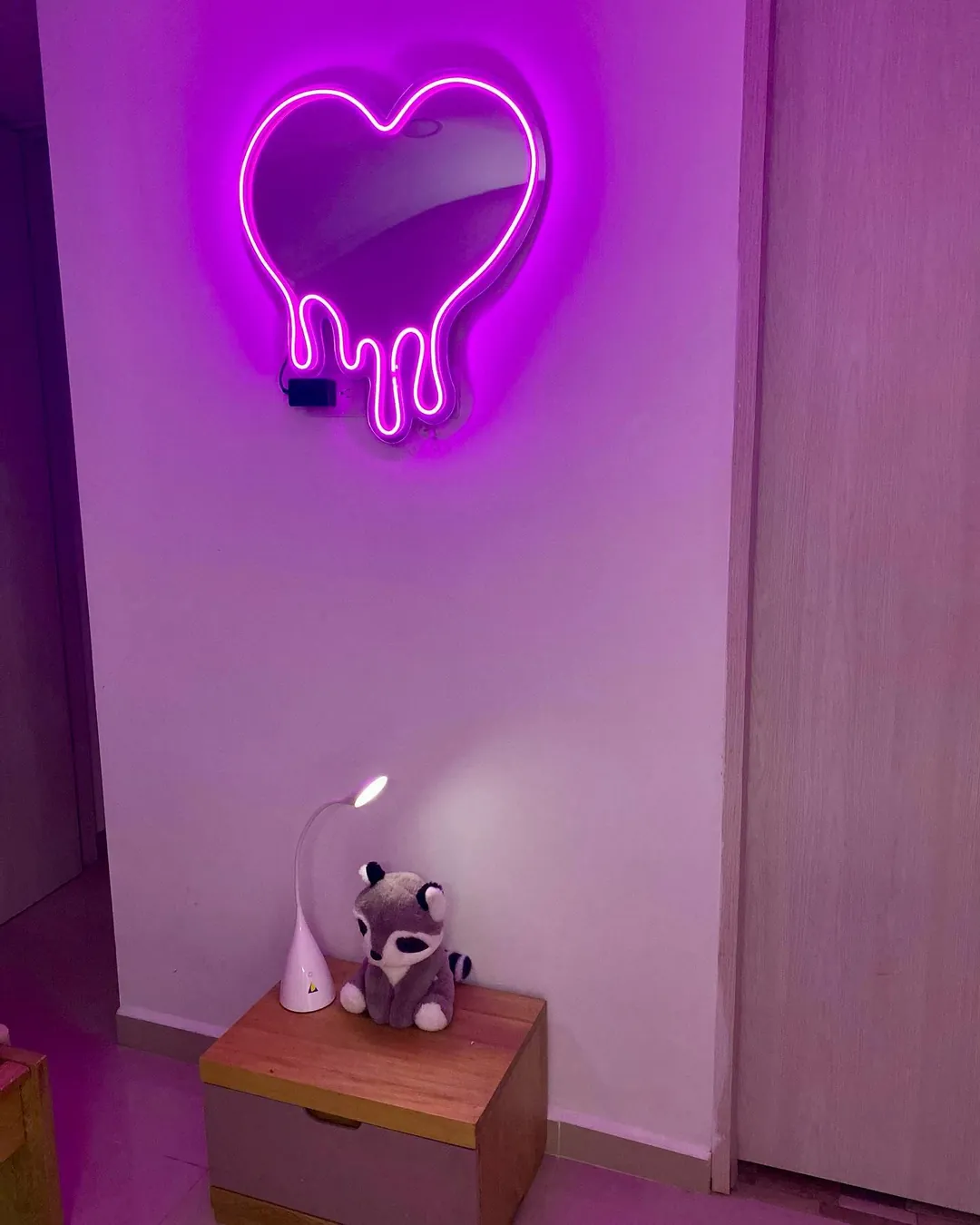 Espejo acrílico con forma de corazón iluminado en morado en una habitación
